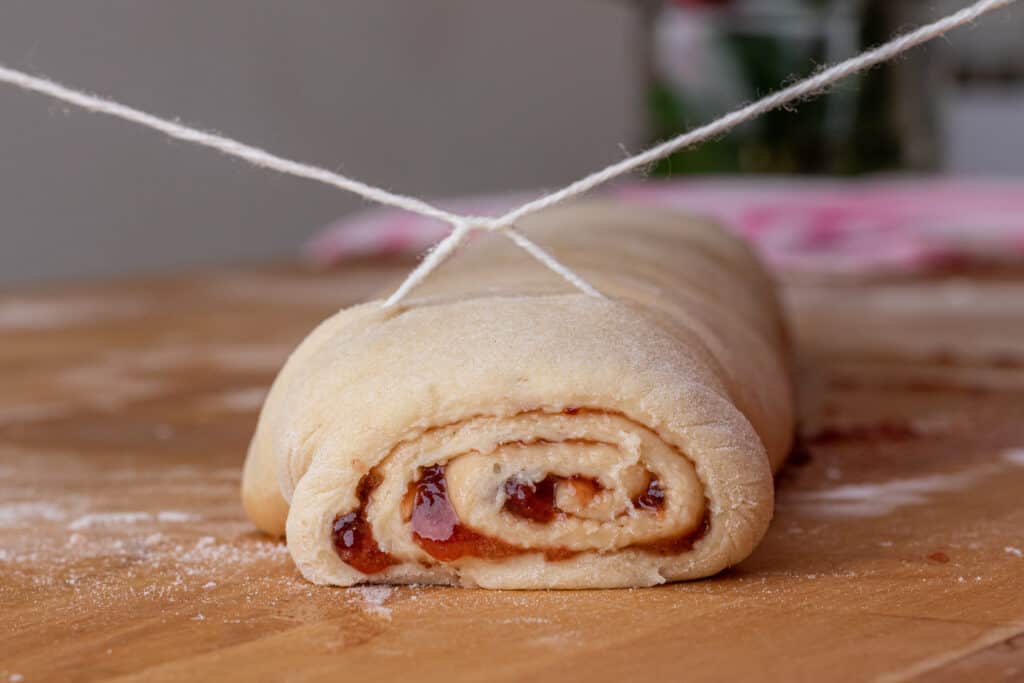string cutting into strawberries and cream sweet rolls 