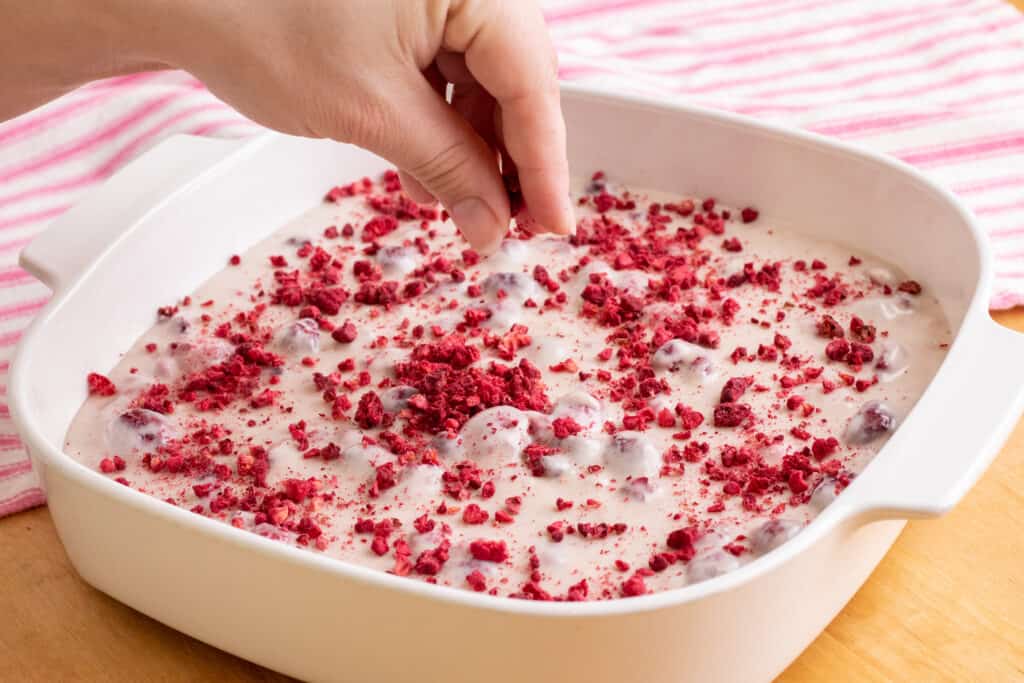 hand sprinkling freeze dried raspberries onto the fudge