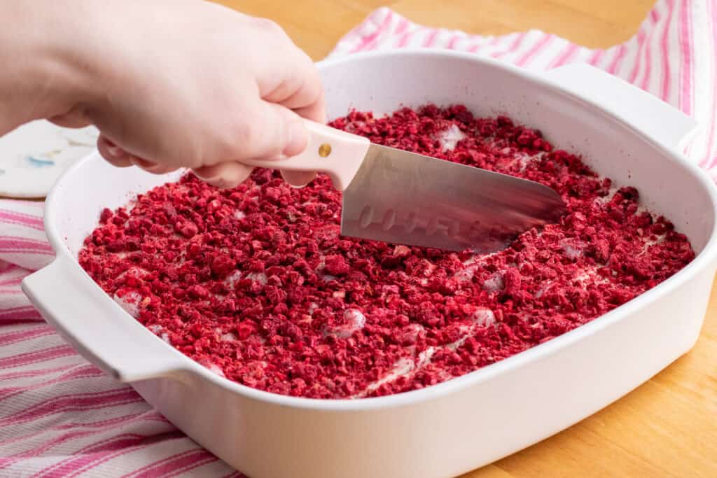 hand cutting white chocolate raspberry fudge into slices with knife