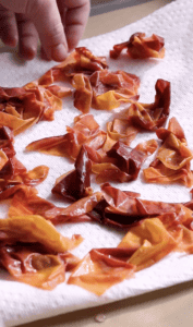 person spreading peach skins on a paper towel to dry