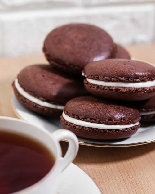 plate of hot chocolate macarons with a cup of tea